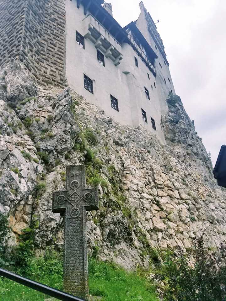 A cross tombstone in front of Bran Castle