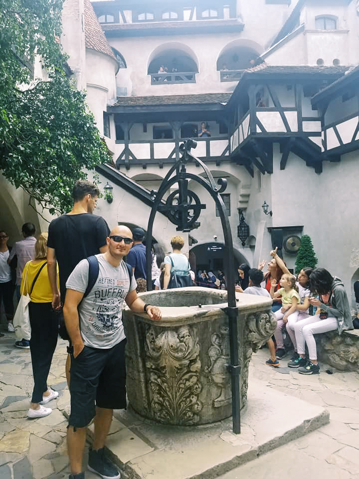 A man poses beside a well in the castle courtyard