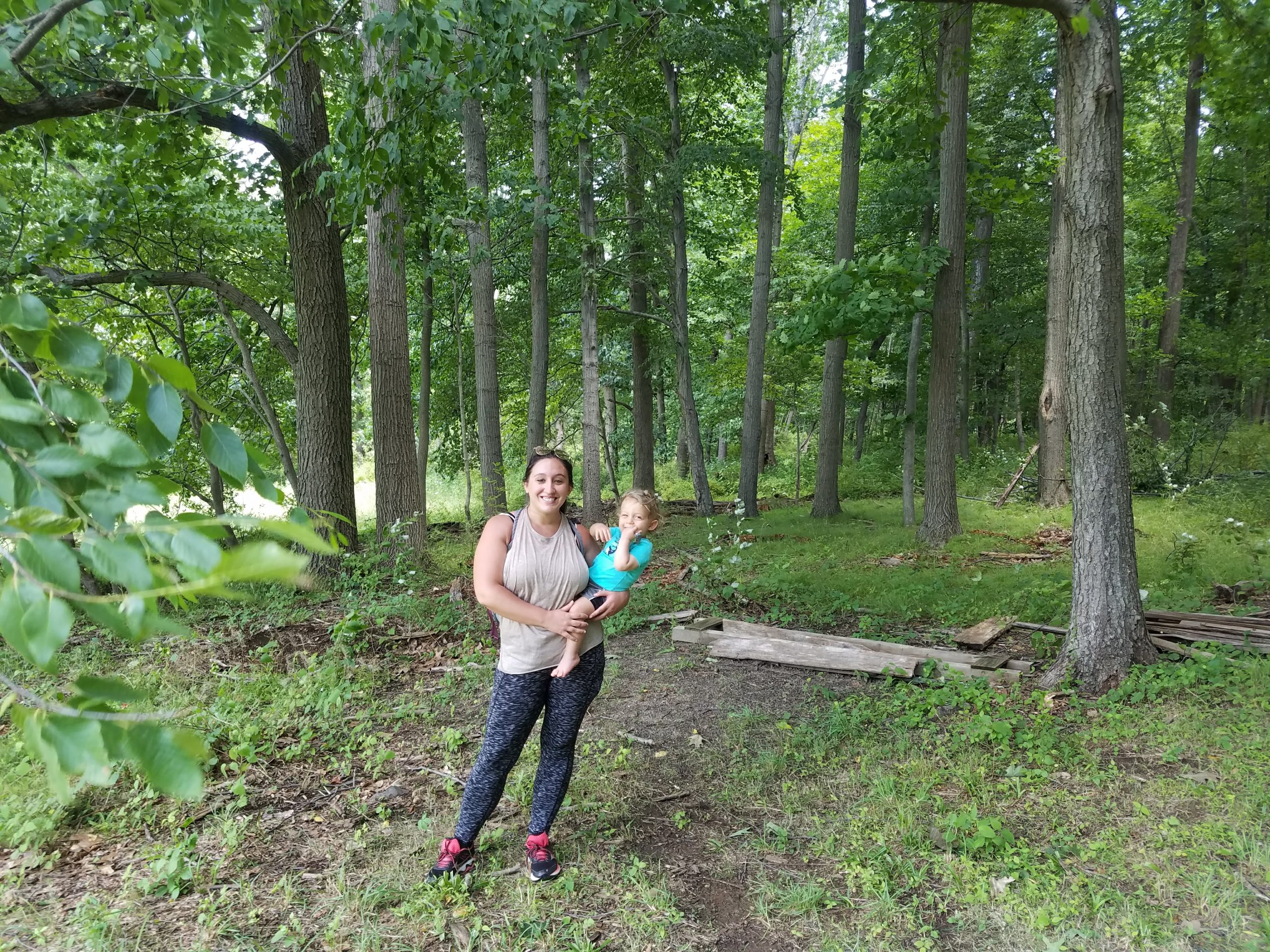 A woman and child stand in the middle of the forest in Jockey Hollow Park