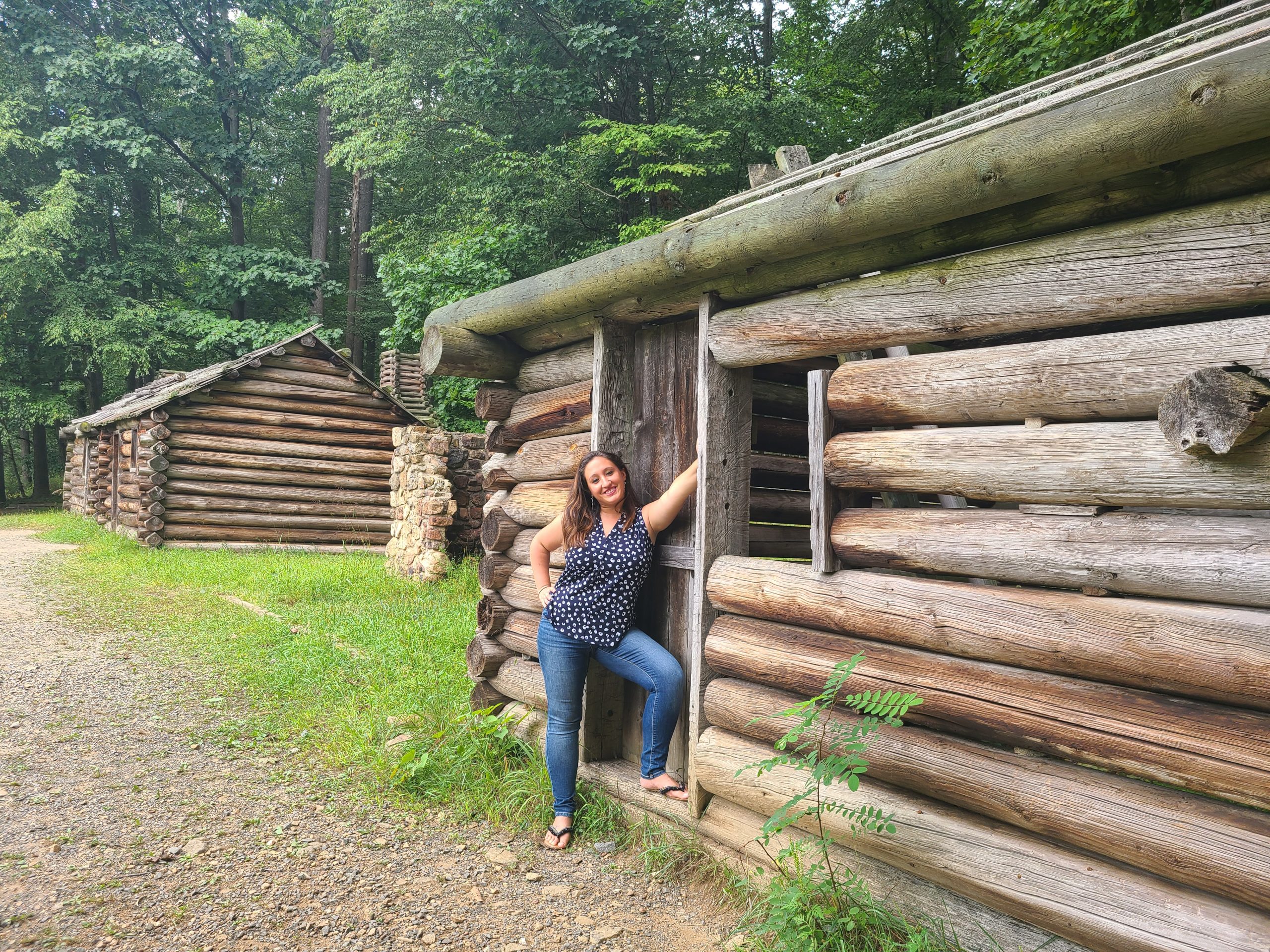 A woman poses next to a recreation of a cabin in Jockey Hollow Park