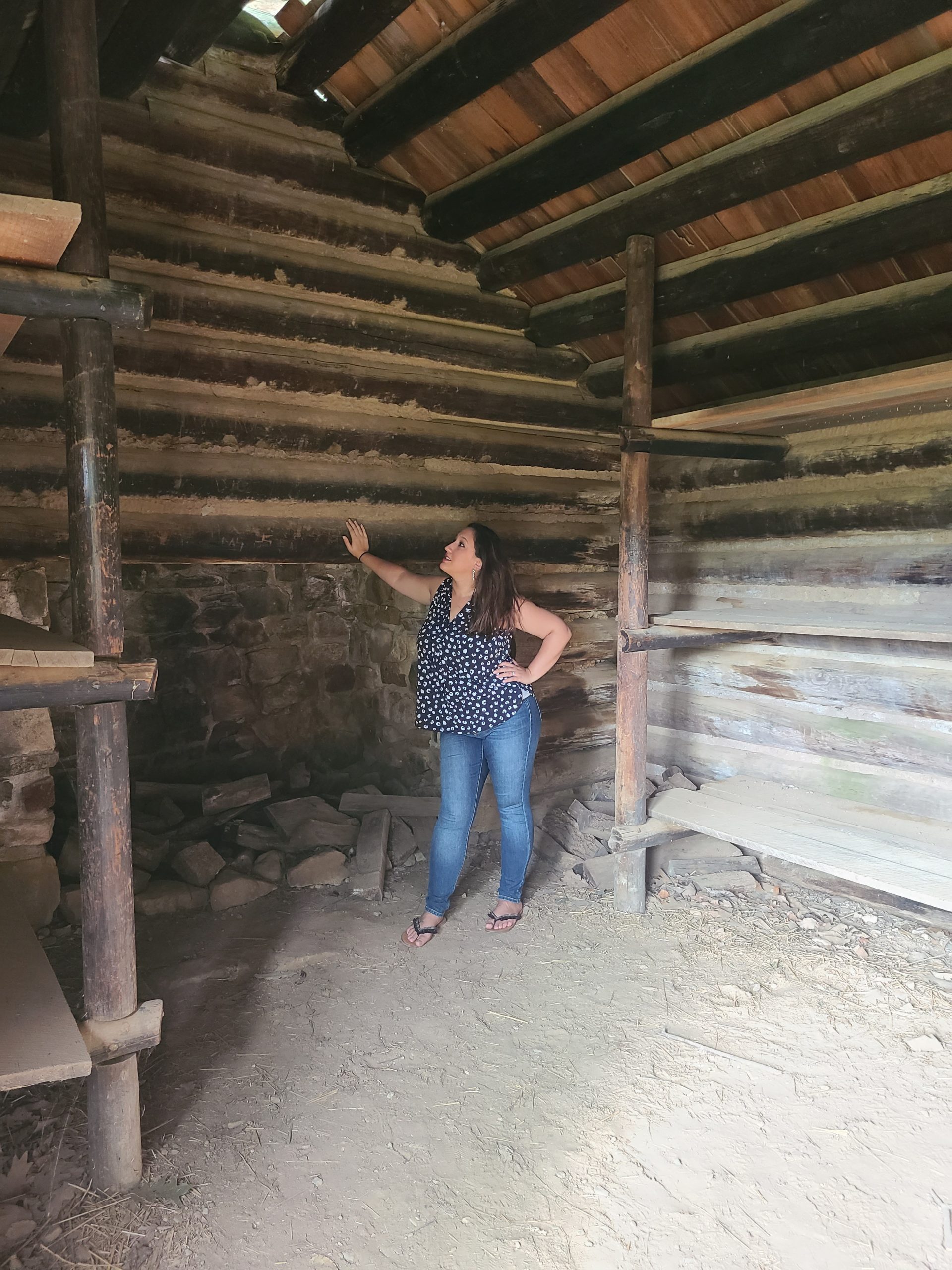 A woman looks up at the wooden walls of a cabin 