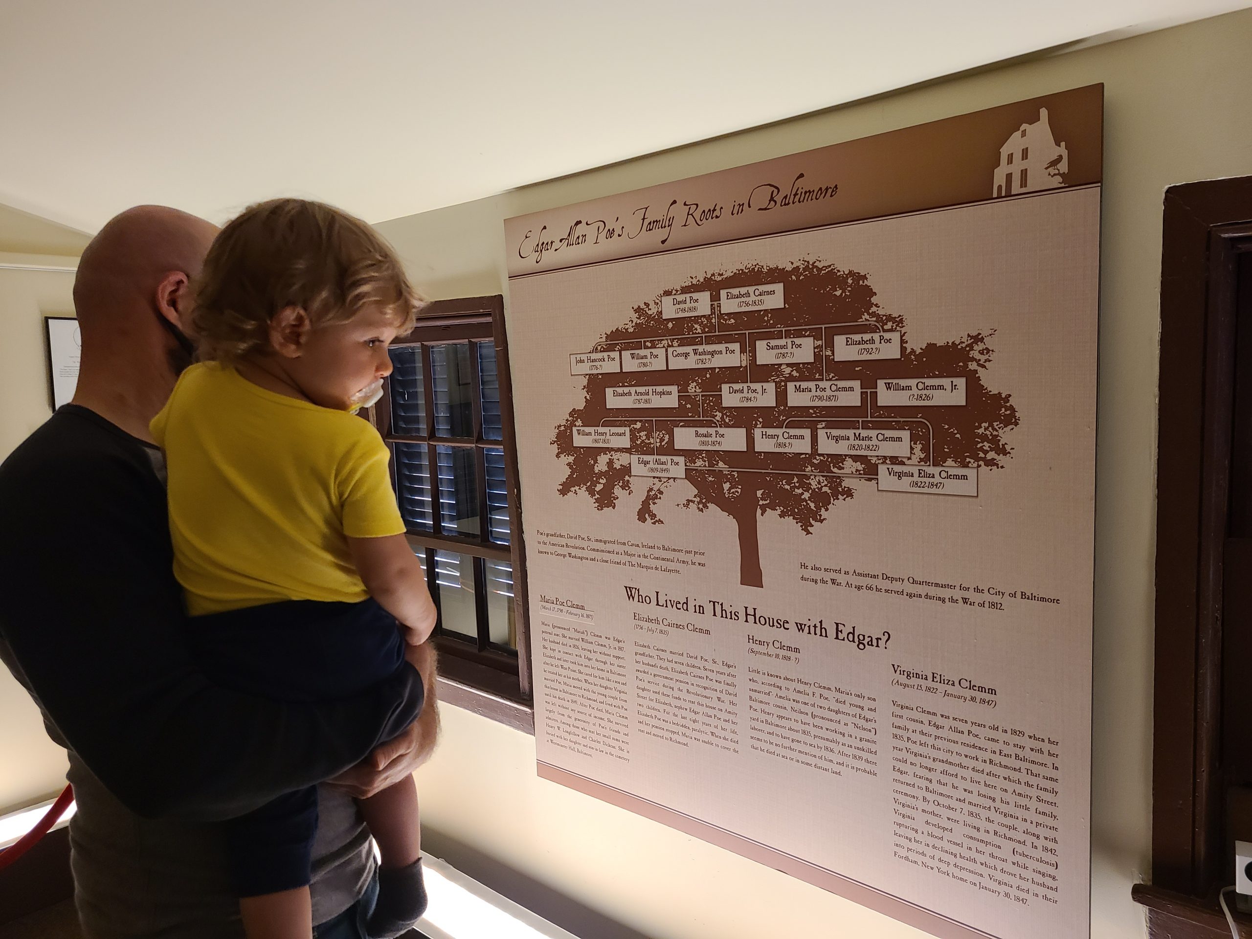 A man and child looking at a sign in the Edgar Allan Poe museum