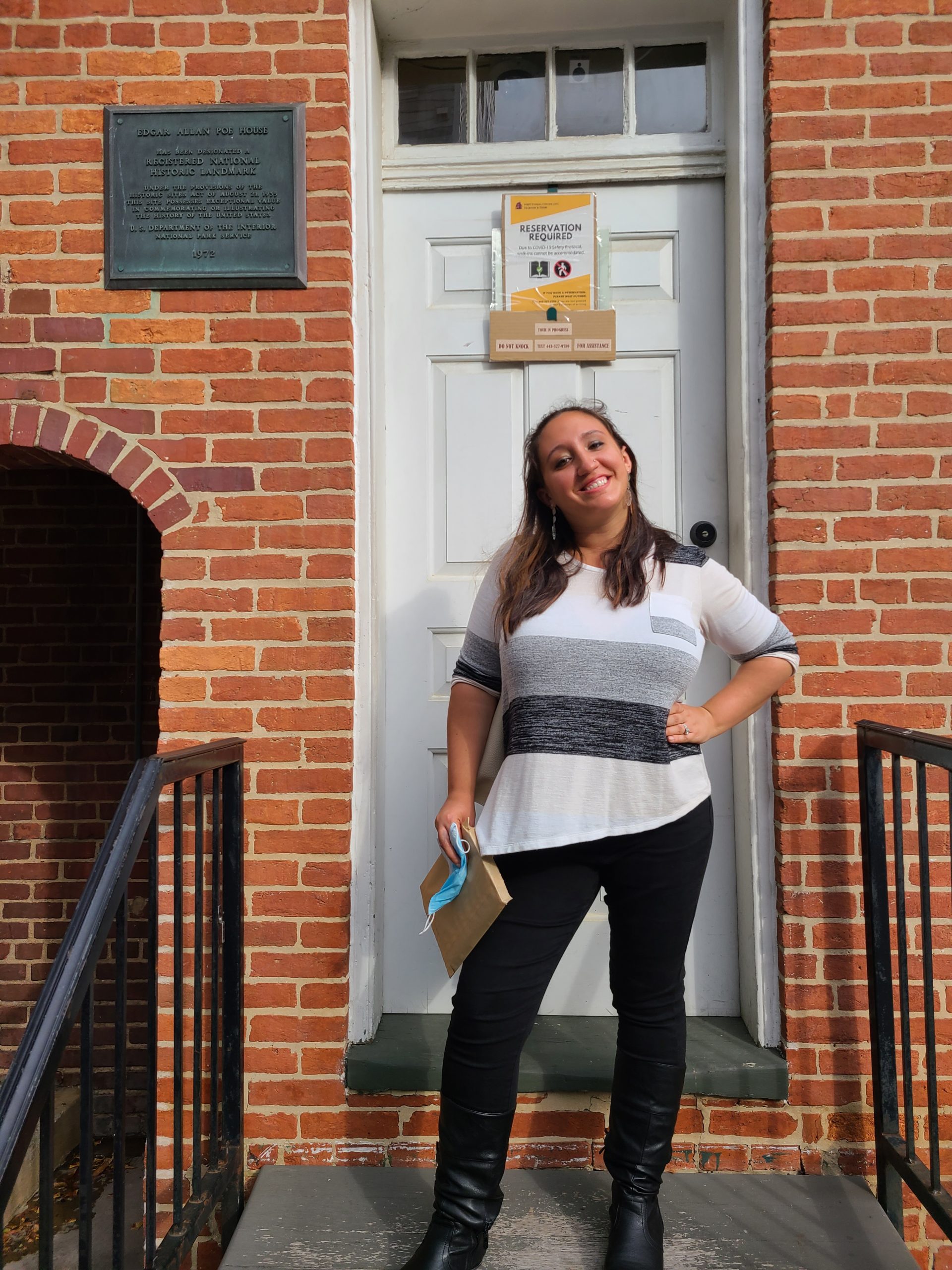 A woman posing outside the door of the Edgar Allan Poe House