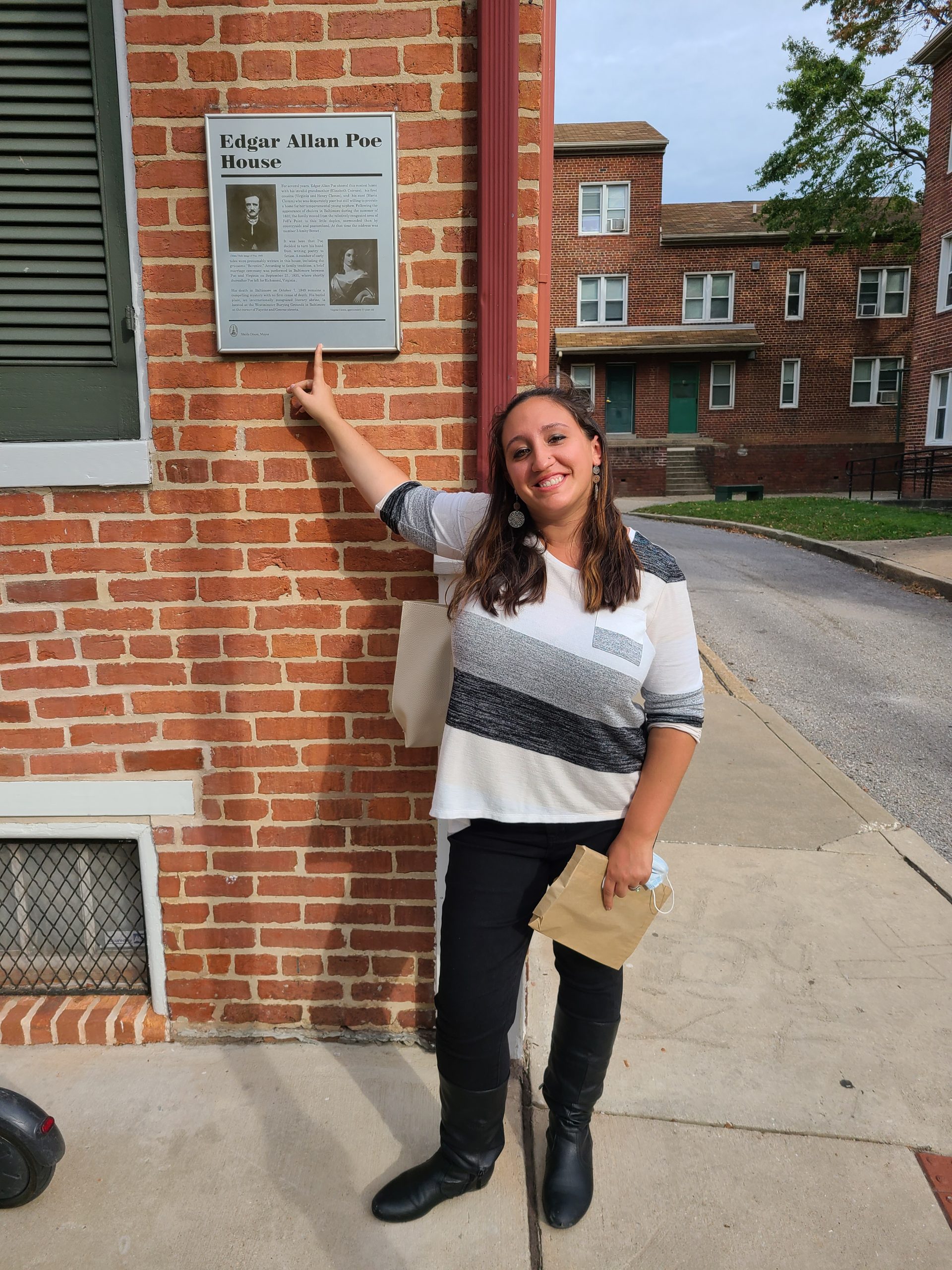 A woman poses outside the Edgar Allen Poe House