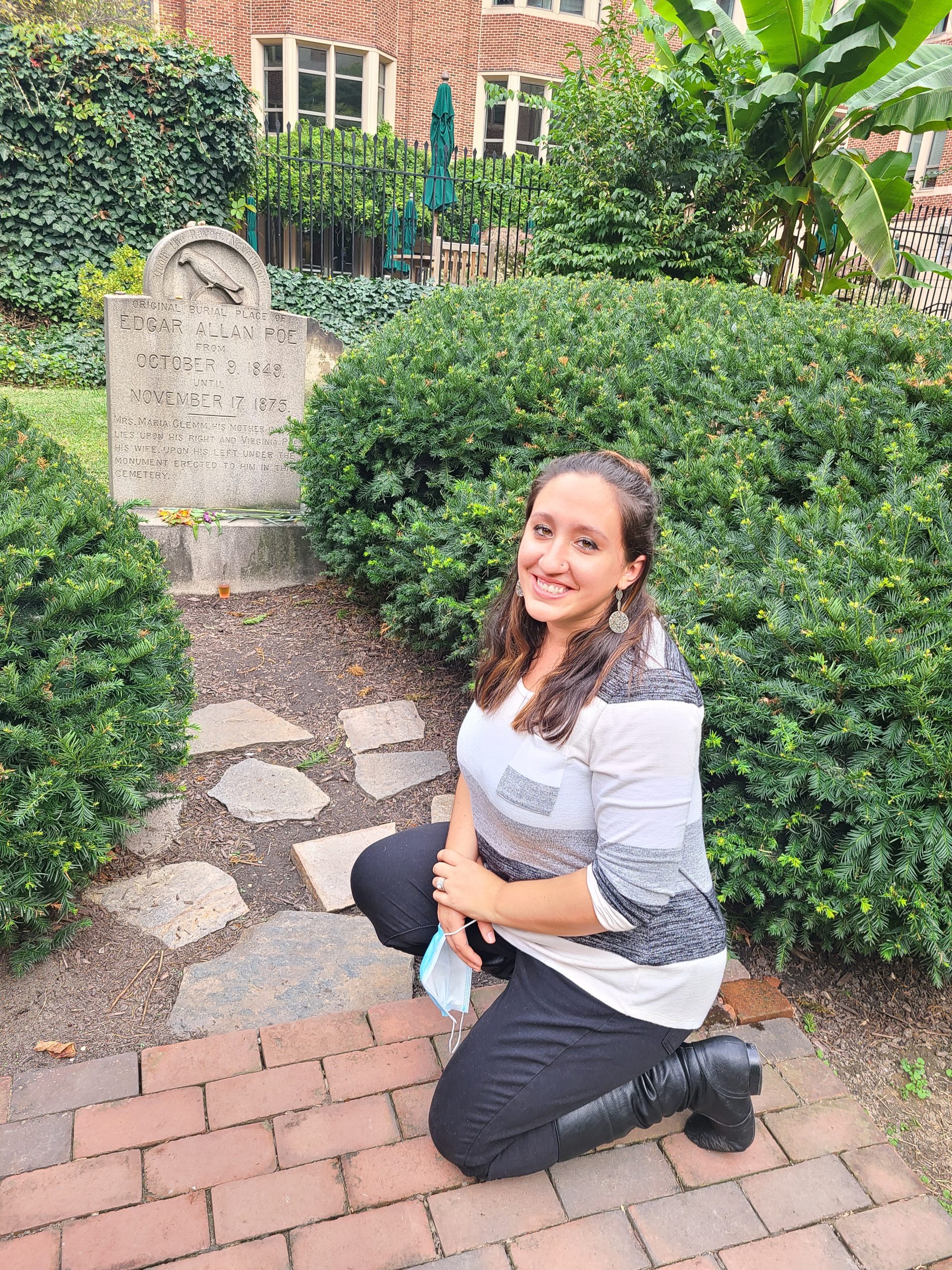 A woman posing next to Edgar Allan Poe's grave