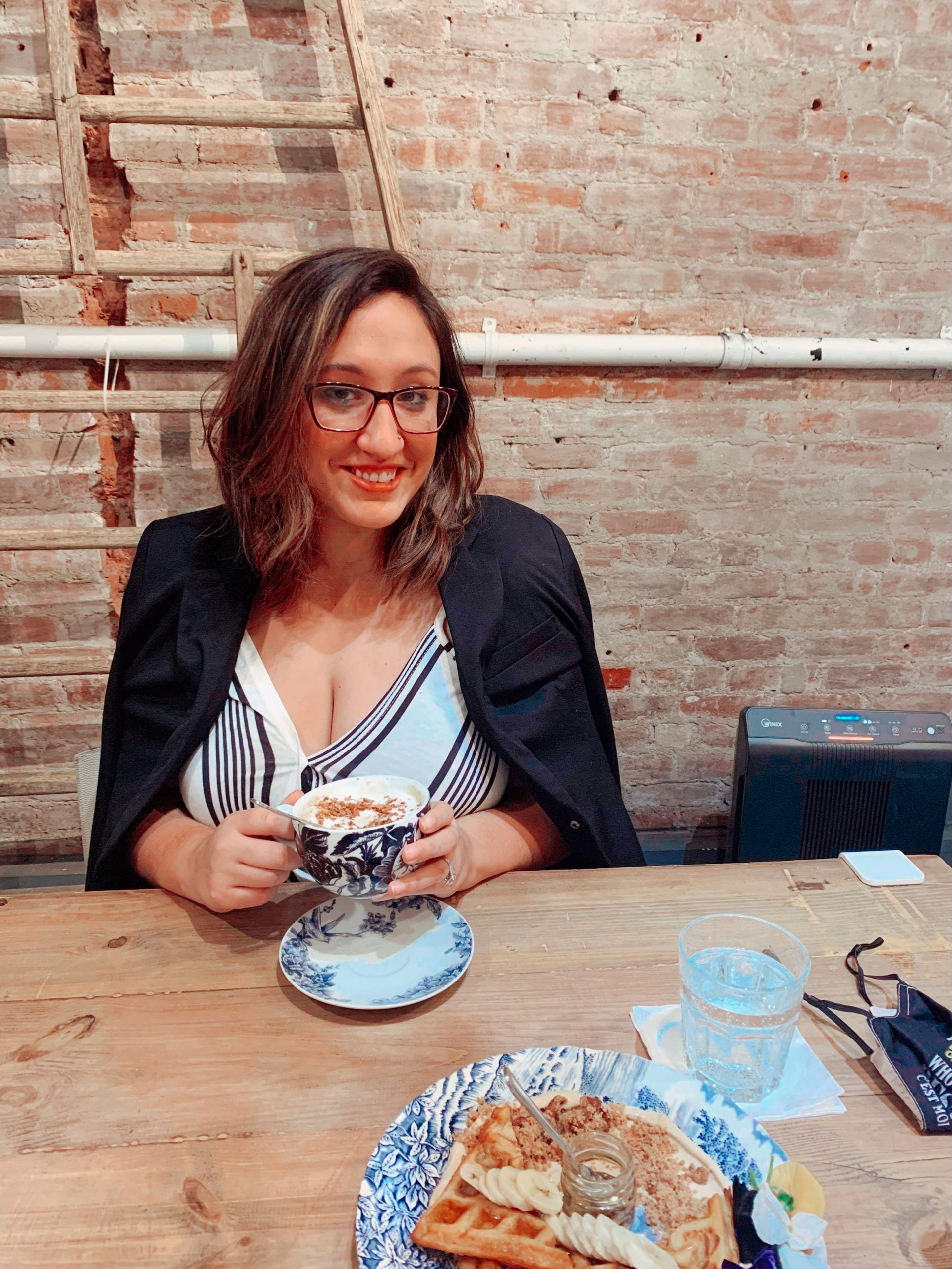 A woman sits with a cup of coffee at Maman cafe