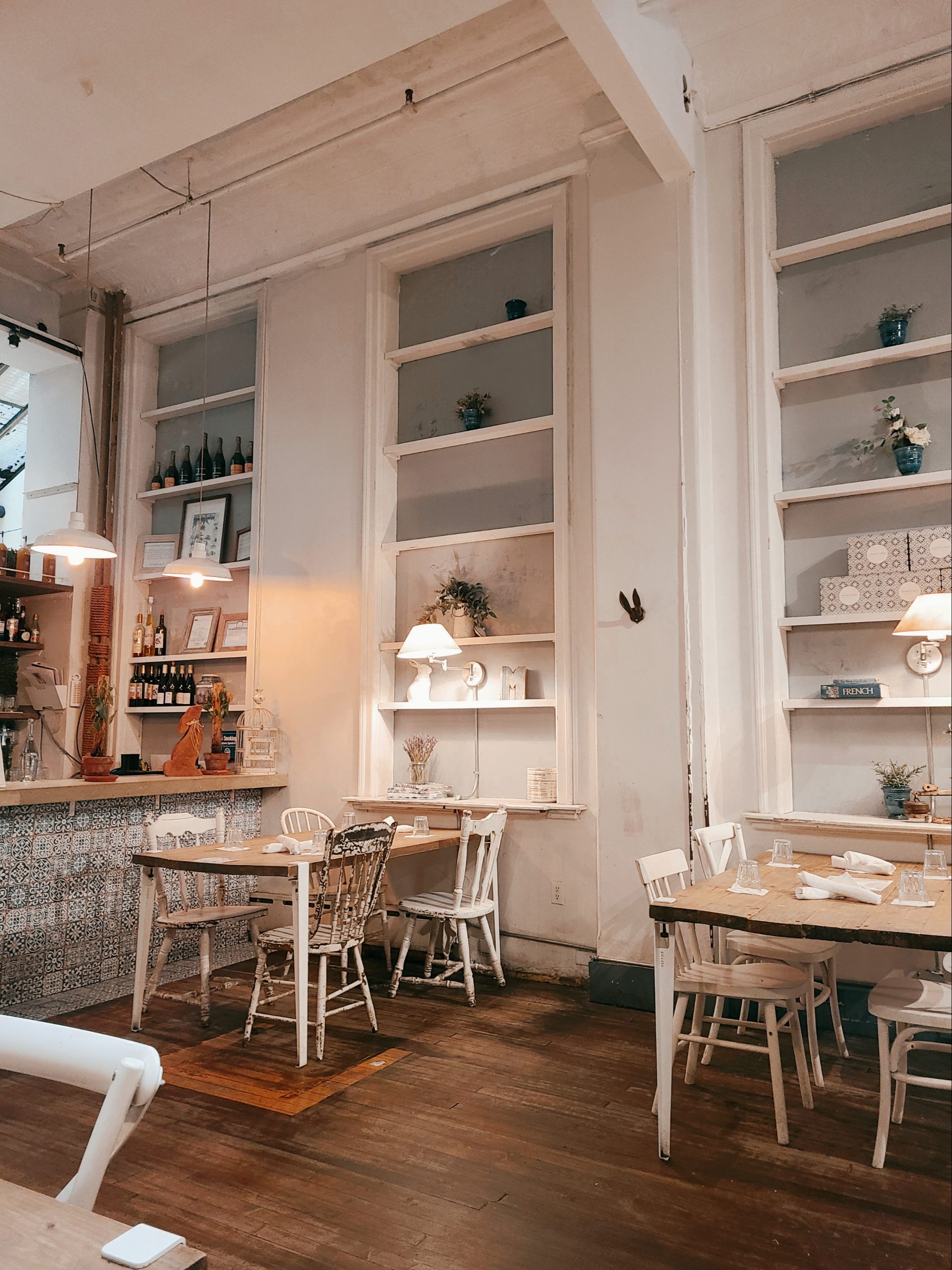 A photo of the interior of Maman cafe, several white tables and chairs are spaced around the room 