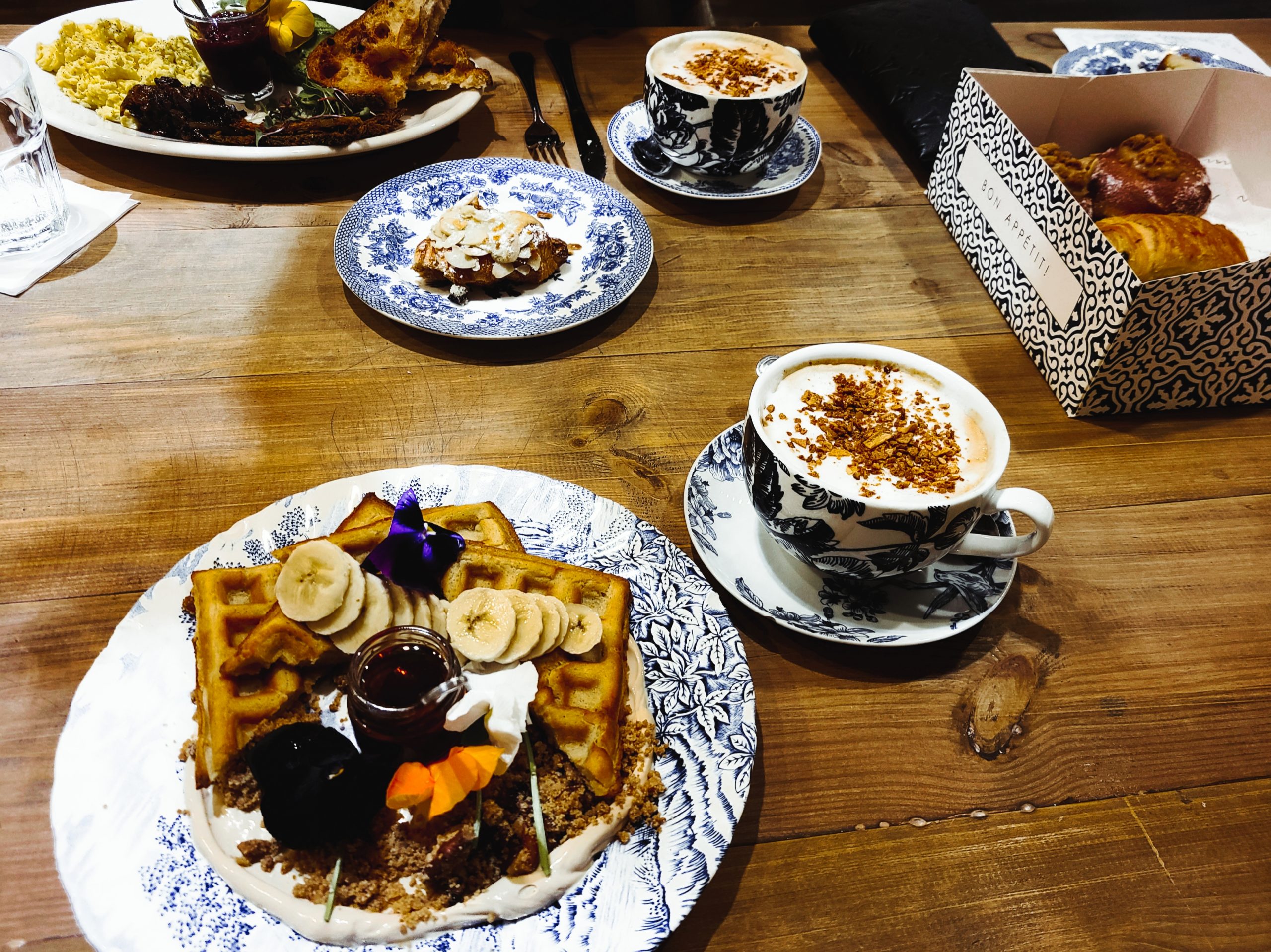 A table filled with plates of pastries and cups of coffee