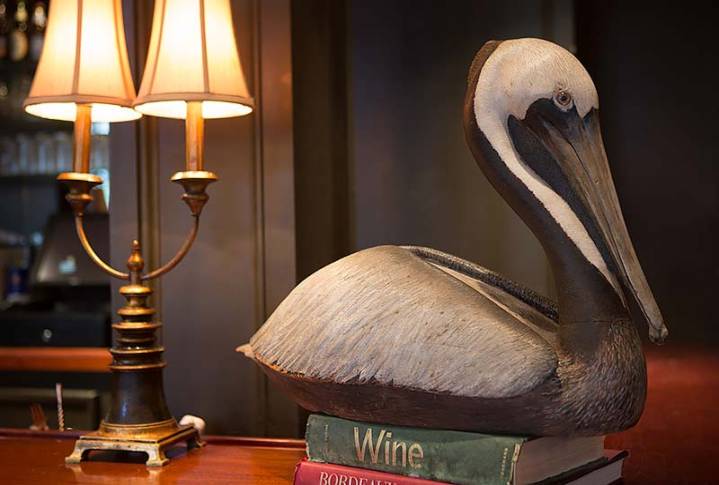 A statue of a pelican on a table next to a lamp