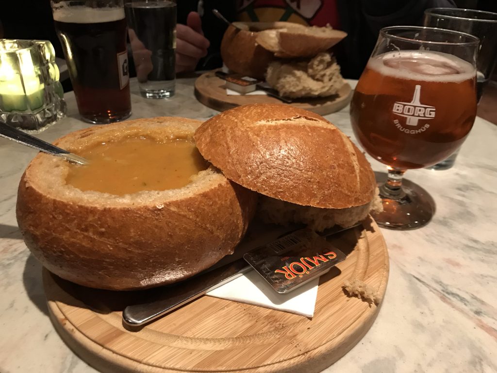 A bread bowl filled with soup and a beer