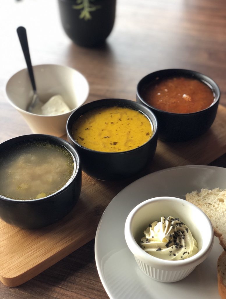 Three bowls of soup with bread and butter