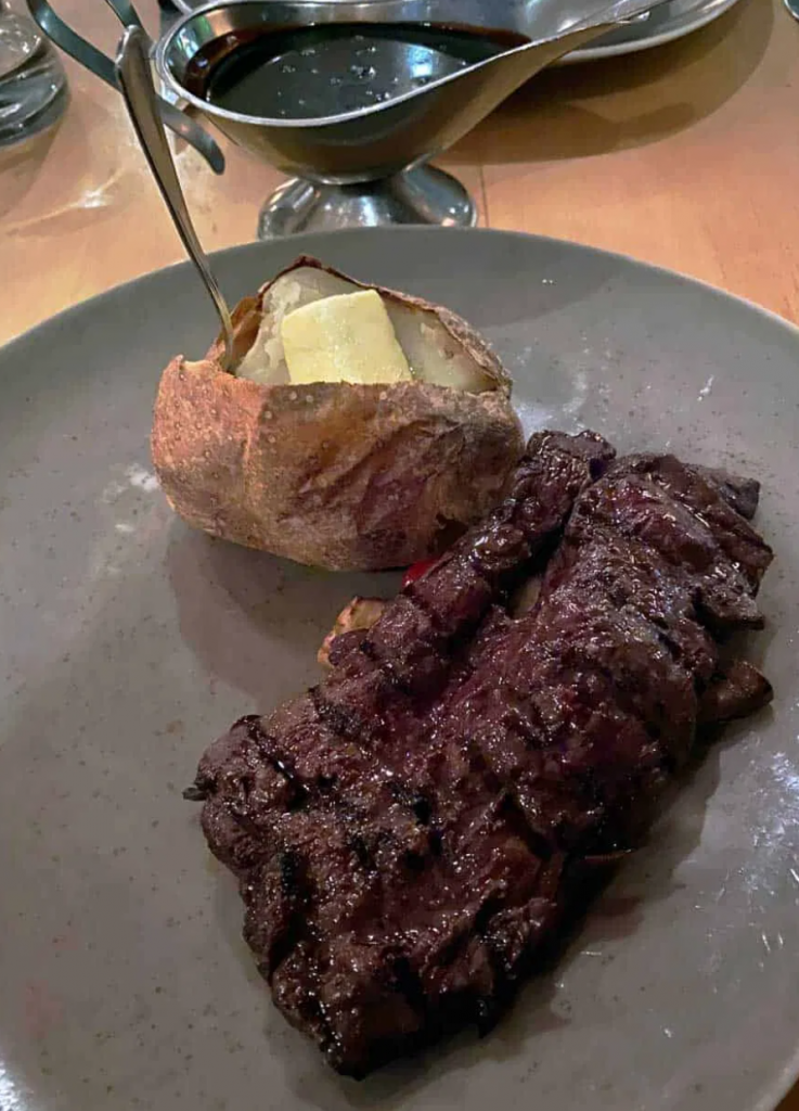 A plate of whale meat steak with a potato