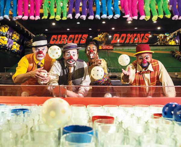A group of clowns playing a ball toss game